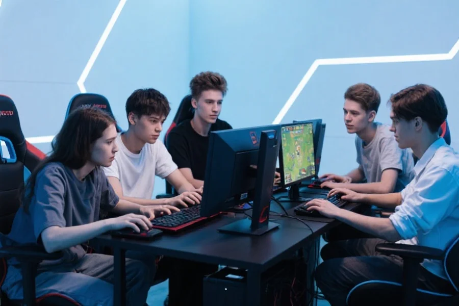 五名年轻玩家聚焦在电脑屏幕前，围坐在一起进行团队合作游戏，背景为简洁的电竞环境